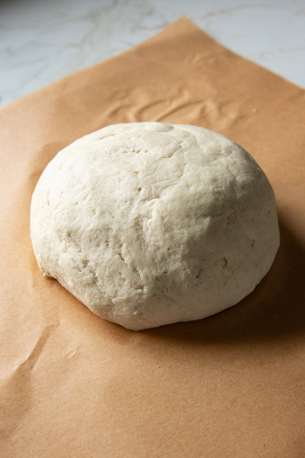 A low FODMAP pizza dough ball sitting on a sheet of parchment paper.