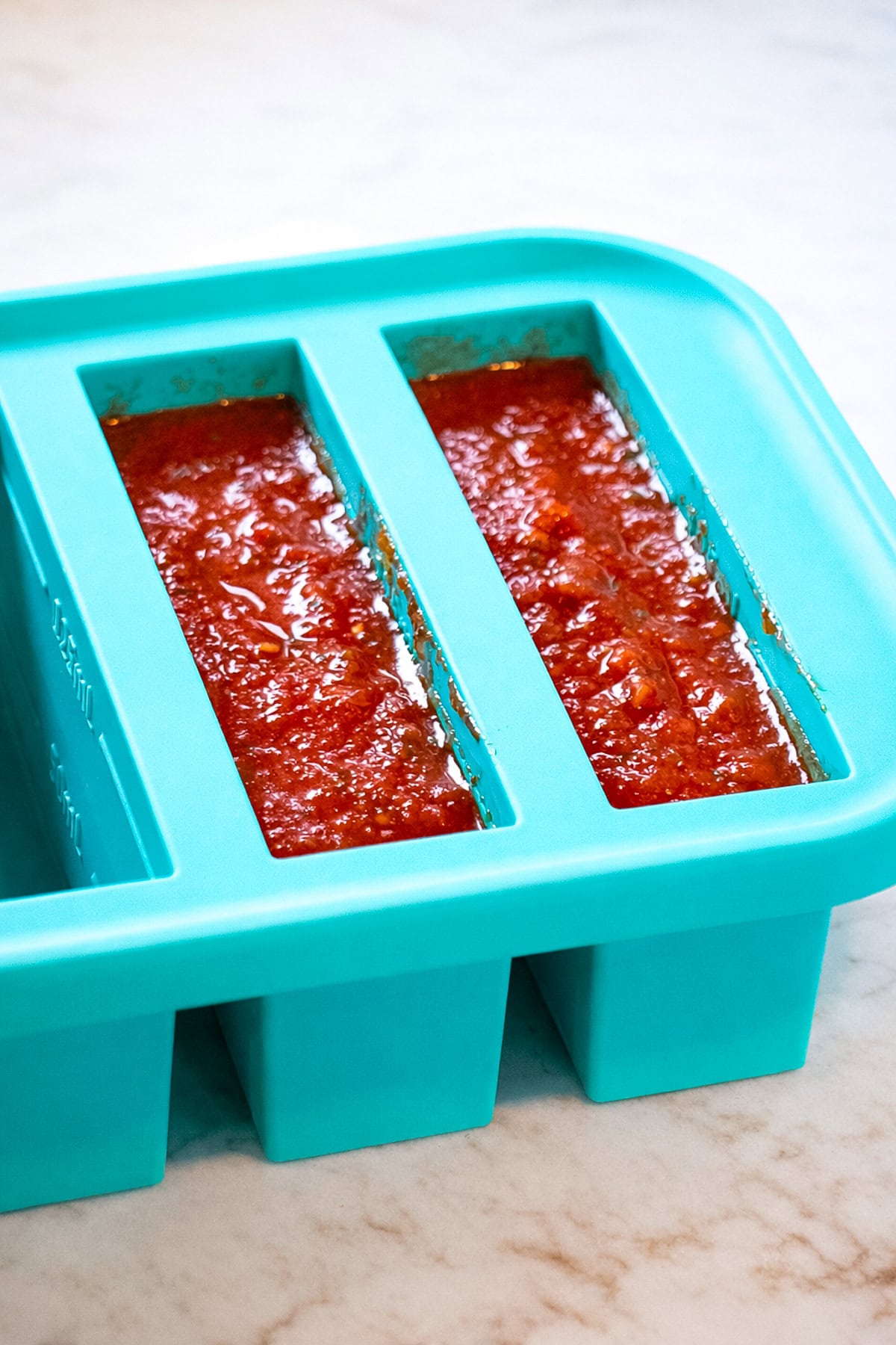 Leftover pasta sauce divided into a pre-portioned silicone tray for freezer storage.