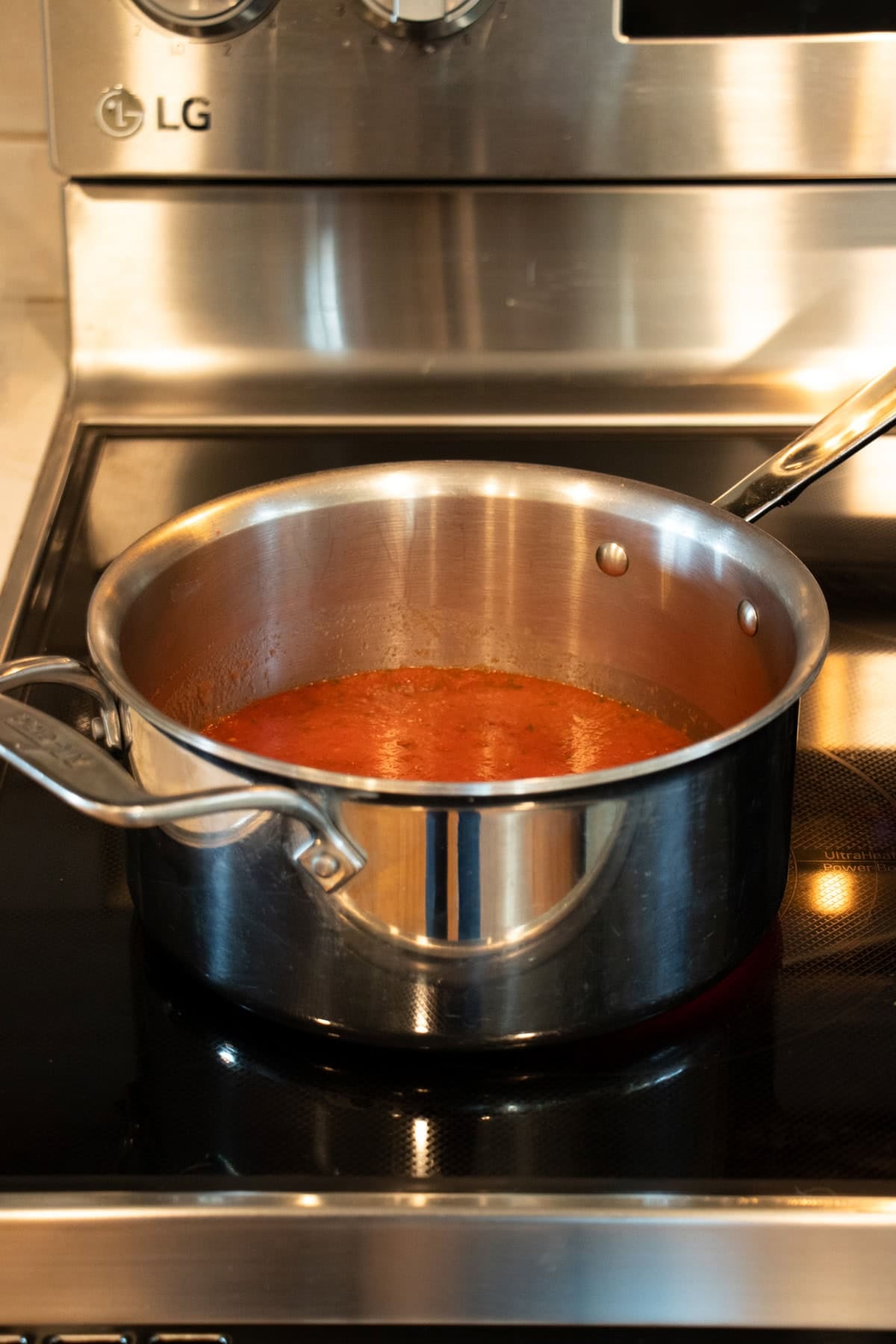 Simmering pizza sauce in a medium saucepan on the stovetop.