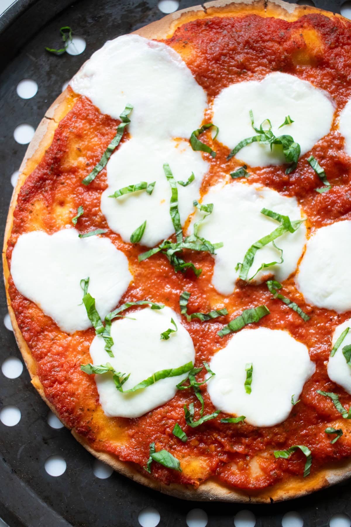 A baked gluten-free pizza with homemade low FODMAP pizza sauce, melted mozzarella, and fresh basil.