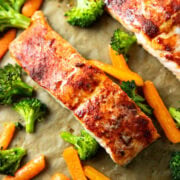 Sheet pan salmon with roasted broccoli and carrots on a parchment-lined baking sheet, seasoned with a smoky spice blend and cooked until roasted and tender
