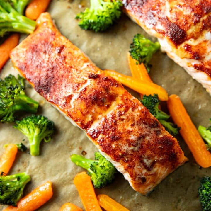 Sheet pan salmon with roasted broccoli and carrots on a parchment-lined baking sheet, seasoned with a smoky spice blend and cooked until roasted and tender