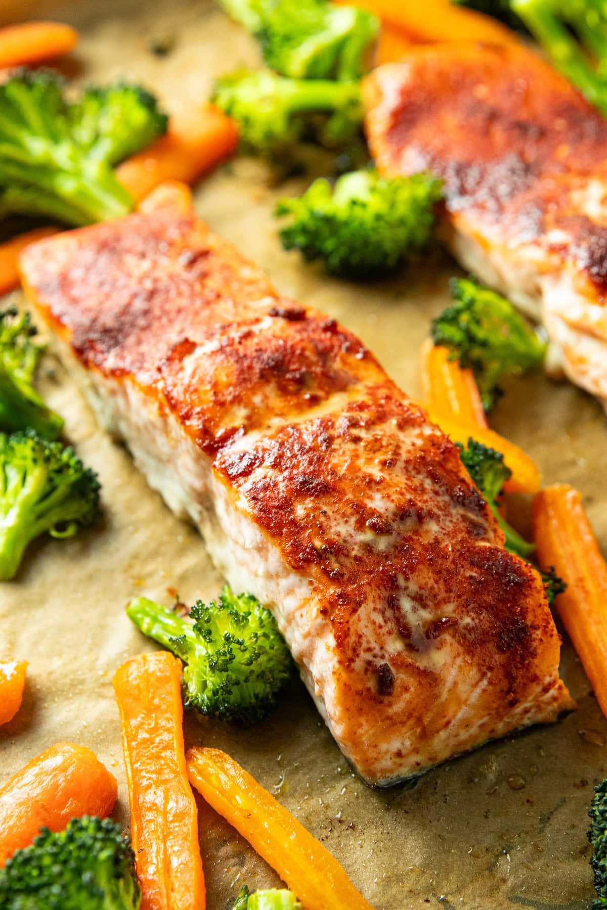 Close-up of sheet pan salmon with smoked paprika seasoning alongside roasted broccoli florets and carrots
