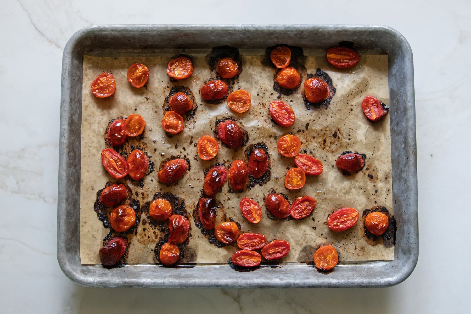 Roasted cherry tomatoes on a sheet pan.