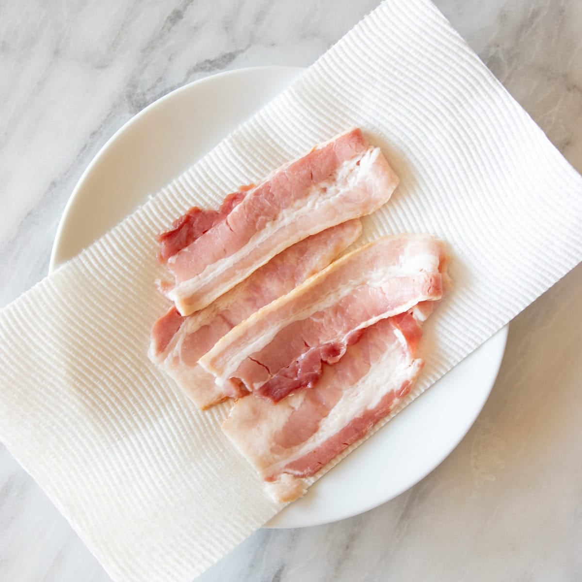 Bacon slices on a paper towel-lined microwavable plate.