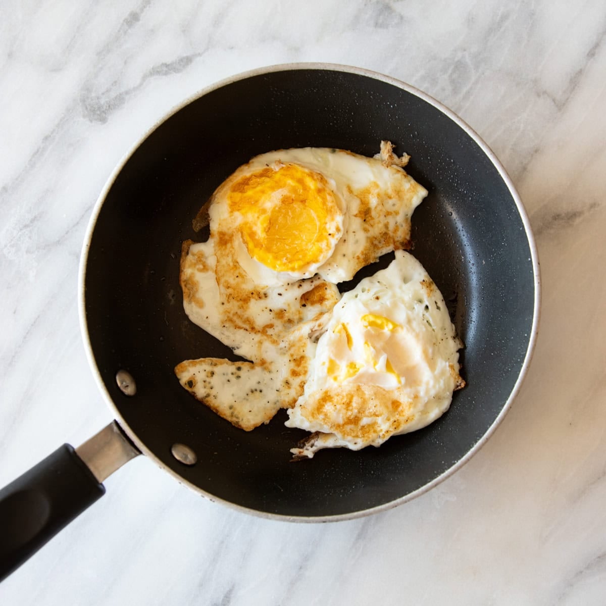 A small nonstick frying pan with two fried eggs.