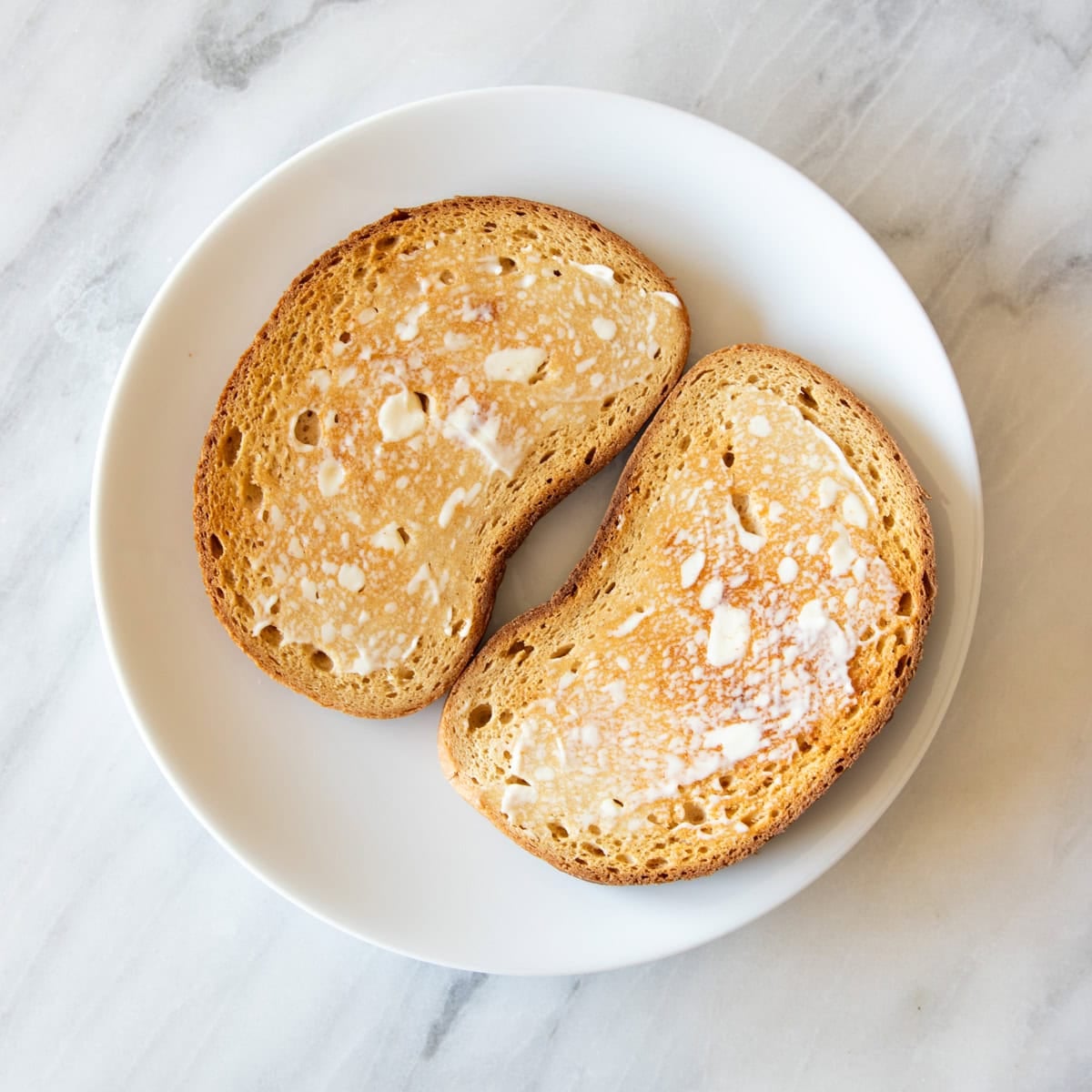 Two slices of toasted Schar bread are spread evenly with mayonnaise.